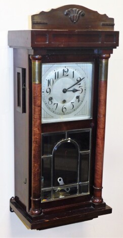 A 1920s mahogany cased wall clock, the rectangular silvered colour dial, key wind with blue hands, in a mahogany frame, with two pillars with brass applied decoration and additional cornice, with eight day movement, 77cm high, 33cm wide, 21cm deep.