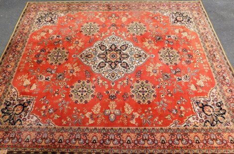 A large Middle Eastern rug, on a cream and orange ground with medallions, 414cm x 320cm.