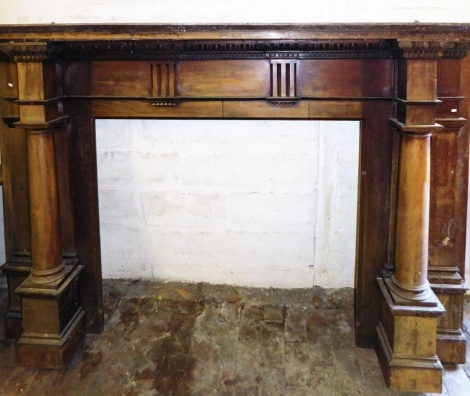 An Edwardian mahogany fireplace, carved with egg and dart floral moulding, over a dentil band and having taper column sides, 145cm high, 233cm wide.