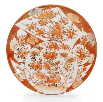 Two Japanese Kutani porcelain dishes, the larger saucer dish decorated with shaped panels of birds in flight, flowering branches, etc., on a red and gold ground, marked Dai Nihon Kutani sei, 36.5cm diameter, and a smaller similar saucer dish marked Kutani - 4