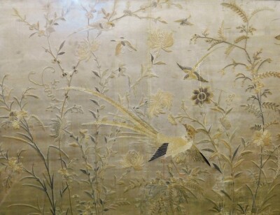 An Oriental silk embroidery, of stylised butterflies and birds among grasses and flowers, on a silvery/brown ground, in a later oak frame, 117cm x 90cm.