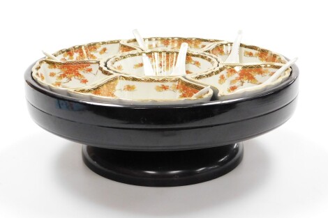 A Japanese hors d'oeuvres dish, with central circular bowl surrounded by six shaped dishes all decorated with red maple, each signed Kyozan, together with eight Chinese porcelain spoons, in an ebonised wooden lazy Susan base, 12cm high, 33cm wide.