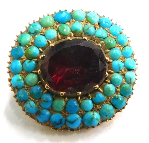 A Victorian brooch, the central oval panel set with red coloured stones, surrounded by two layers of turquoise, inscribed to back AMS ALFAJC, yellow metal unmarked, 2.5cm wide, 5.9g all in.