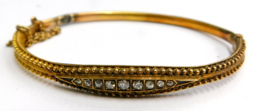 A Victorian hinged bangle, the half hoop design with reeded filigree type decoration, with central diamond set panel, with safety chain on a yellow metal colour band, with later base unmarked, 6cm wide.