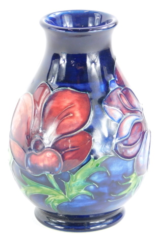 A Moorcroft pottery baluster shaped vase, decorated with poppies on a blue ground, impress marks to underside, 14cm high.