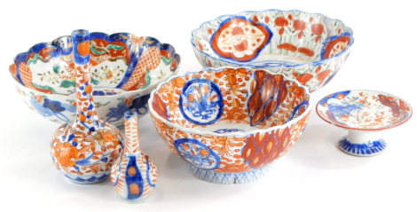 A collection of Japanese Imari porcelain, to include three bowls, each with a shaped edge, a stand and two bottle shaped vases. (6, AF)