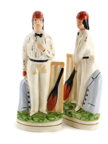 A pair of reproduction Staffordshire figures, each modelled in the form of a cricketer, 25cm high.