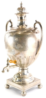 A late 19th/early 20thC silver plated two handled samovar, engraved with scrolls, surrounding a vacant cartouche, with part fluted body, complete with burner section (wedged), on a square foot with bun feet, 59cm high.