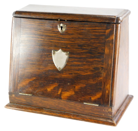 An Edwardian oak stationary box, the hinged lid enclosing a fitted interior, applied with a vacant silver plated shield shaped cartouche, 32cm wide.