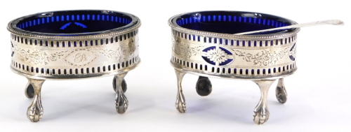 A pair of George III silver oval salts, each with pierced and engraved decoration of flowers, scrolls, etc., bearing initial B and with blue glass liners on shaped legs with ball and claw feet, London 1785 and an associated salt spoon, weighable silver 3¼