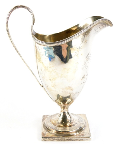 A William IV silver helmet shaped cream jug, with a reeded border and handle, on a square base, London 1835, 3¾oz, 14.5cm high.