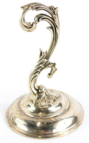 A late 19th/early 20thC silver pocketwatch stand, with scroll cast support on a domed foot, loaded, (AF), 11cm high.