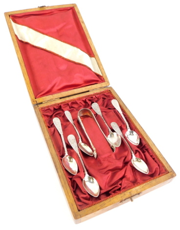 A set of six continental silver coloured metal teaspoons and matching sugar tongs, each decorated with scrolls, flowers, etc., and with a spirally fluted stem, the oak case adapted.