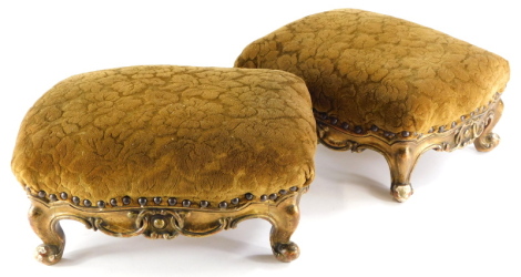 A pair of 19thC gilt wood footstools, each with a padded seat on cabriole legs, 44cm wide.