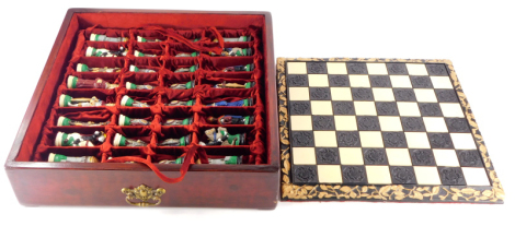 A elaborate chess set, comprising board with carved border and chess pieces, each a medieval style figure, handpainted in fitted outer case.