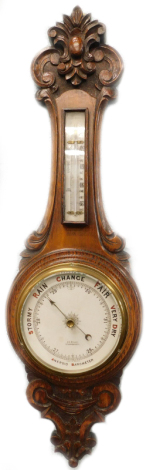 An early 20thC carved oak android barometer, the dial stamped J E Beale of Bournemouth, 78cm high.