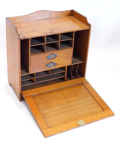 An Edwardian oak table top desk, with raised gallery, the panelled fall enclosing a fitted interior, etc., 55cm high, 56cm wide.