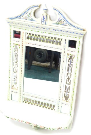 A late 19th/ early 20thC wall mirror, later painted in cream, with flowers, etc., with pierced borders surrounded a rectangular plate and a shelf, 81cm high, 84cm wide.