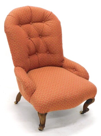 A Victorian mahogany button back armchair, upholstered in red and gold geometric patterned fabric, on scroll carved legs.