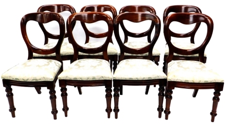 A set of eight Victorian mahogany balloon back dining chairs, each with a padded seat on turned tapering legs.