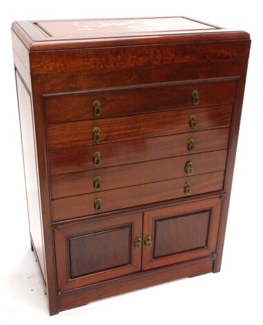 An oriental Chinese hardwood needlework cabinet, the hinged lid inlaid with mother of pearl, with prunus and birds, enclosing a baize lined interior, above a false drawer and four further drawers and two panelled doors, on a plinth, 89cm high, 63cm wide, 