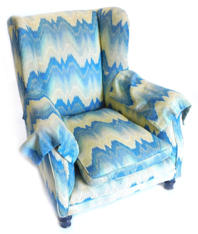 A Victorian wingback chair, upholstered in striped fabric on turned legs.