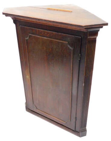 A 19thC oak corner cabinet, with a moulded cornice above a single panel door, flanked by readed pilasters, 107cm high, 86cm wide.