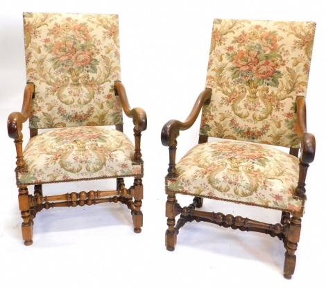 A pair of 19thC French open armchairs, each with a padded back and seat, upholstered in tapestry type fabric, on turned supports with stretchers.