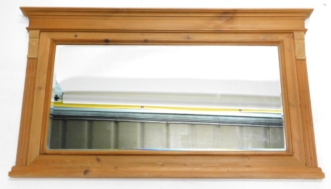 A pine overmantel mirror, with a moulded cornice above a bevelled glass plate, flanked by readed pilasters, 119cm wide, 67cm high.