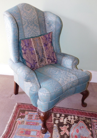 A high wingback upholstered armchair, in George I style, with blue Damask upholstery and carved cabriole legs, 85cm wide over arms.