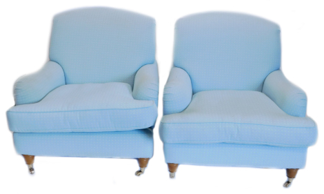 A pair of armchairs in the manner of George Smith, upholstered in pale blue fabric, on turned legs with brass castors.