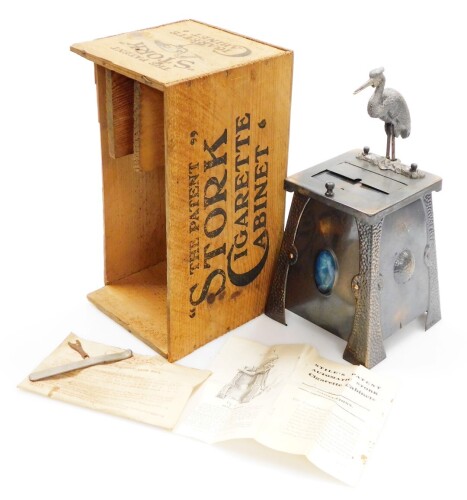 The 'Stork' patent cigarette cabinet, being a hammered and anodised example with oval Ruskin enamel centres, complete with most of the original wooden packaging box, the instruction booklet for 'Stile's Patent', and bar lever in envelope, 29cm high.