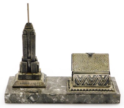 An Art Deco cigarette dispensing desk stand, formed with a cast spelter model of the Empire State Building New York on a black marble base, 19cm high, 22cm wide.