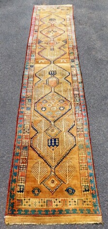 An early 20thC Sarab design carpet runner, with two stylised borders, enclosing a central floral medallion field, with trees, 460cm x 86cm.