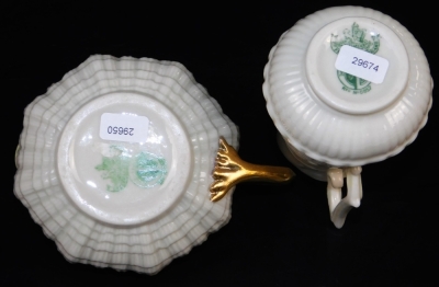 A group of first green mark Belleek wares, comprising of Tridacna creamer with yellow band and gilt shamrocks, new shell sugar basin with highlighted band and creamer en-suite and a helmet shaped creamer with a J shaped handle and scale moulding. (4) - 5