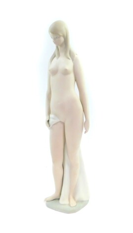 A Lladro bisque porcelain figure of a naked lady, modelled in standing pose with a draped sheet, printed mark, 47cm high.