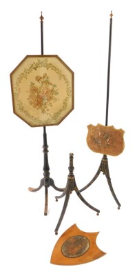 An early 19thC ebonised pole screen, the octagonal framed screen silk stitched with roses and other flowers, within a repeating foliate border, raised on a baluster turned stem over three cabriole legs, 153.5cm high, further pole screen with shield shaped