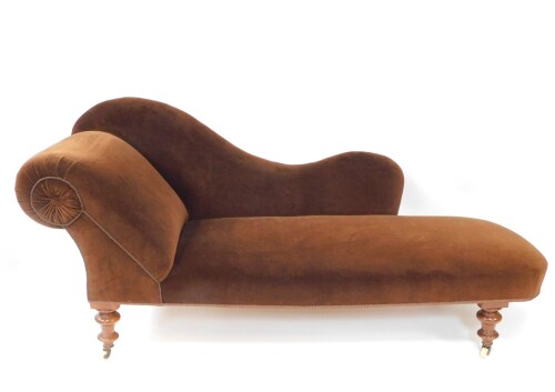 A Victorian mahogany chaise longue, upholstered in brown velour, raised on turned legs, brass capped on castors, 192cm wide.