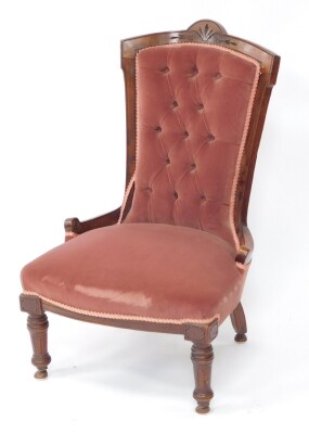 A Victorian mahogany nursing chair, upholstered in red button back velour, with over stuffed seat, raised on turned and fluted legs.