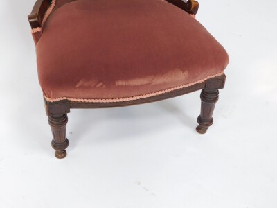 A Victorian mahogany nursing chair, upholstered in red button back velour, with over stuffed seat, raised on turned and fluted legs. - 2