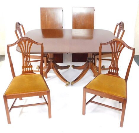 A Georgian style mahogany twin pedestal dining table, with one additional leaf, raised on twin columns each over four fluted out swept legs, brass capped on castors, 73cm high, 154cm wide, 242cm extended, 112cm deep, together with four Hepplewhite mahogan