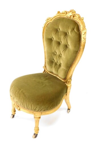 A Victorian parcel gilt balloon back nursing chair, upholstered in green button back velour with over stuffed seat, raised on turned and fluted legs, on ceramic castors.