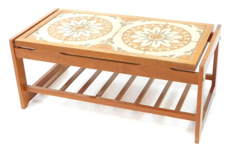 A 1960's tile top teak coffee table, possibly Danish, the top with eight tiles in a floral pattern, raised on straight united by a slatted under tier, 40cm high, 95cm wide, 48cm deep.