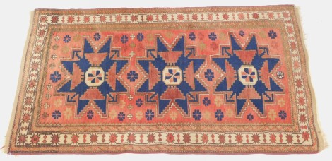 A Kurdish red ground rug, with three star shaped medallions, within a repeating floral border, 190cm x 108cm.