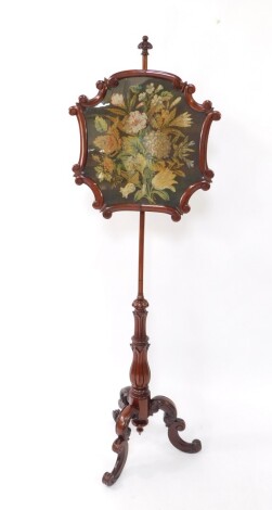 A Victorian mahogany pole screen, the shaped central section embroidered with a petit point floral decoration, surmounted by a carved and partially gadrooned orb finial, with plain turned stem and acanthus leaf moulding beneath, on double scroll legs term