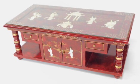 A Chinese red lacquer and Shibyama coffee table, the top decorated with pagodas and figures in a garden, above four turned columns, a pair of frieze doors flanked by a pair of short frieze drawers, raised on a plinth base and turned feet, 47cm high, 126.5