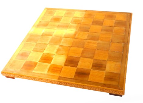 An Art Deco oak and beech chess board, the sides with floral carving, 45cm diameter.