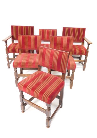 A set of six oak dining chairs, each with overstuffed backs and seats, in red lined material, on turned front legs, terminating in compressed orb feet joined by front horizontal stretchers, comprising a pair of carvers and four single chairs.