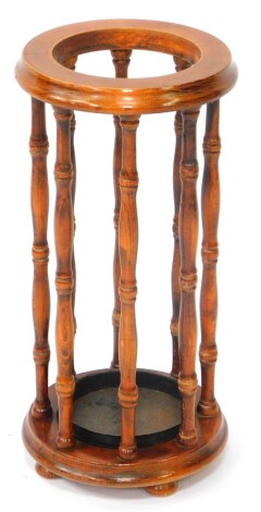 An oak circular umbrella and stick stand , with metal drip tray and spindle frame, raised on a circle base over three bun feet. 53cm high.