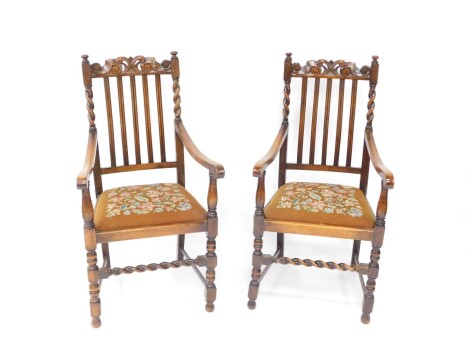 A pair of early 20th century oak carver chairs, with floral woolwork tapestry drop in seats, raised on turned legs united by box stretchers.